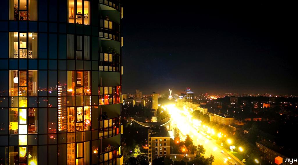 Житловий комплекс Aria з панорамними вікнами та видом на нічне місто. Сучасна архітектура та освітлення фасаду.