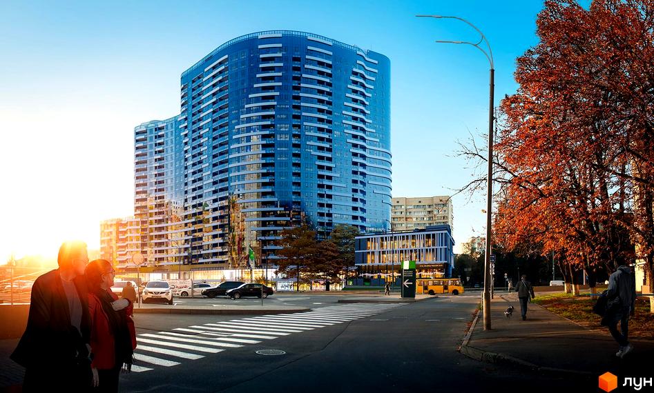 Житловий комплекс Aria - це вигнута будівля з синіми скляними фасадами та численними балконами. Навколо комплексу розташована міська інфраструктура з пішохідним переходом та деревами.