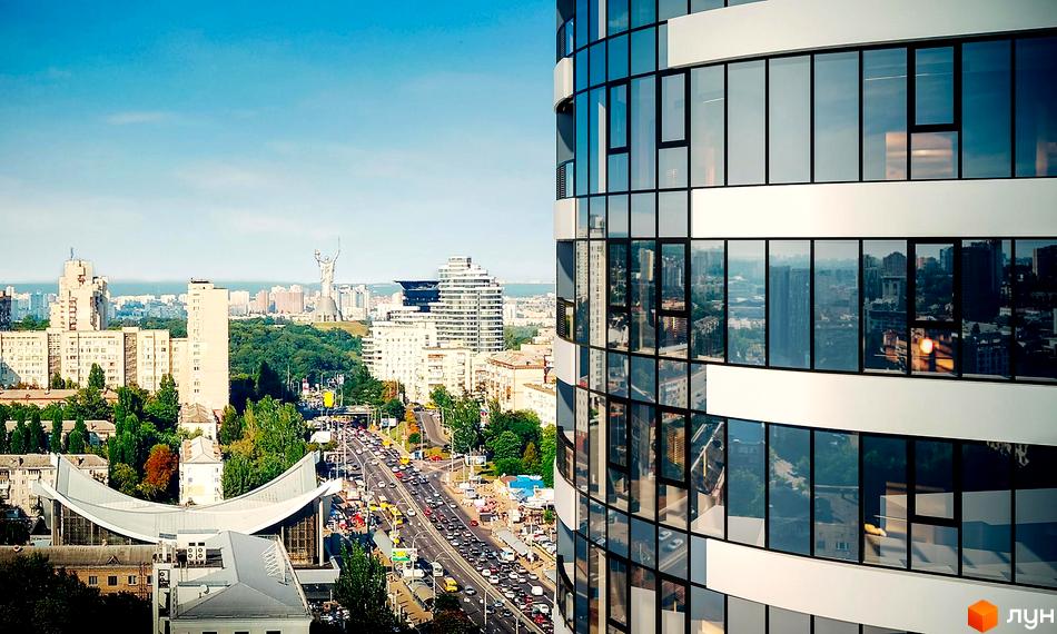 Житловий комплекс Aria: сучасна архітектура з панорамними вікнами та видом на міський пейзаж з автомобільною дорогою.