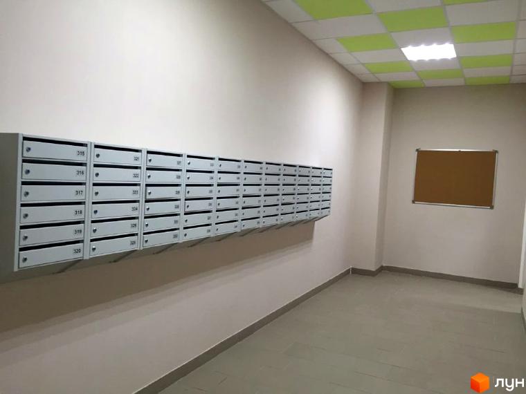 Коридор в ЖК Green park з поштовими скриньками та дошкою оголошень. Світлі стіни, плитка на підлозі та комбінована стеля.