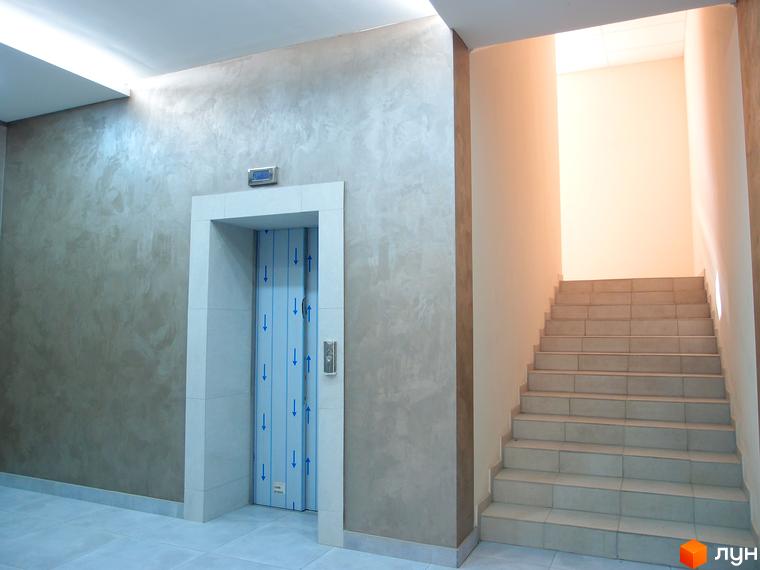 Сучасний інтер'єр житлового комплексу Palladio з ліфтом та сходами. Оздоблення стін під мармур, плитка на підлозі та сходах.