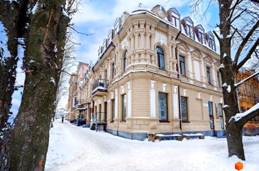 Новобудова на пл. Соборна, 6 взимку. Фасад будівлі світлий, з ліпниною, оточений засніженою вулицею.