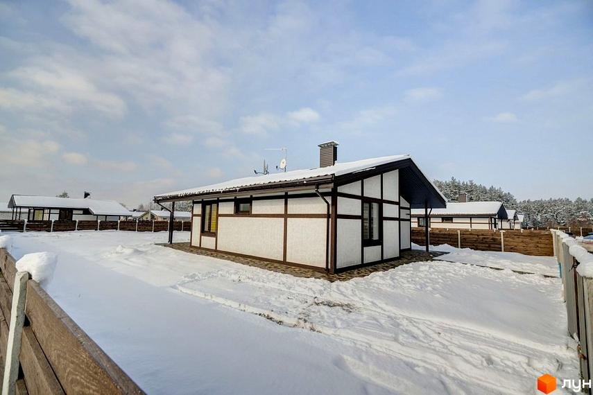 Котеджне містечко Удачино: одноповерховий будинок білого кольору з темними балками та засніженим дахом. Прибудинкова територія вкрита снігом.