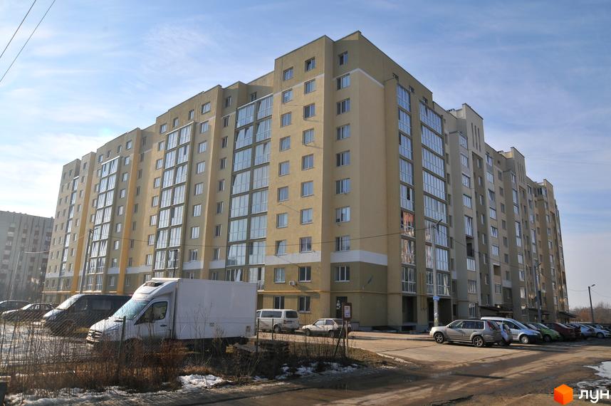 Висотна будівля ЖК на вулиці Роксоляни, 43а з великими вікнами та світлим фасадом. На прибудинковій території припарковані автомобілі.