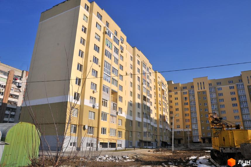 Багатоповерховий будинок жовтого кольору на вулиці Роксоляни, 43а. Будівля має велику кількість вікон, поруч розташована прибудинкова територія.