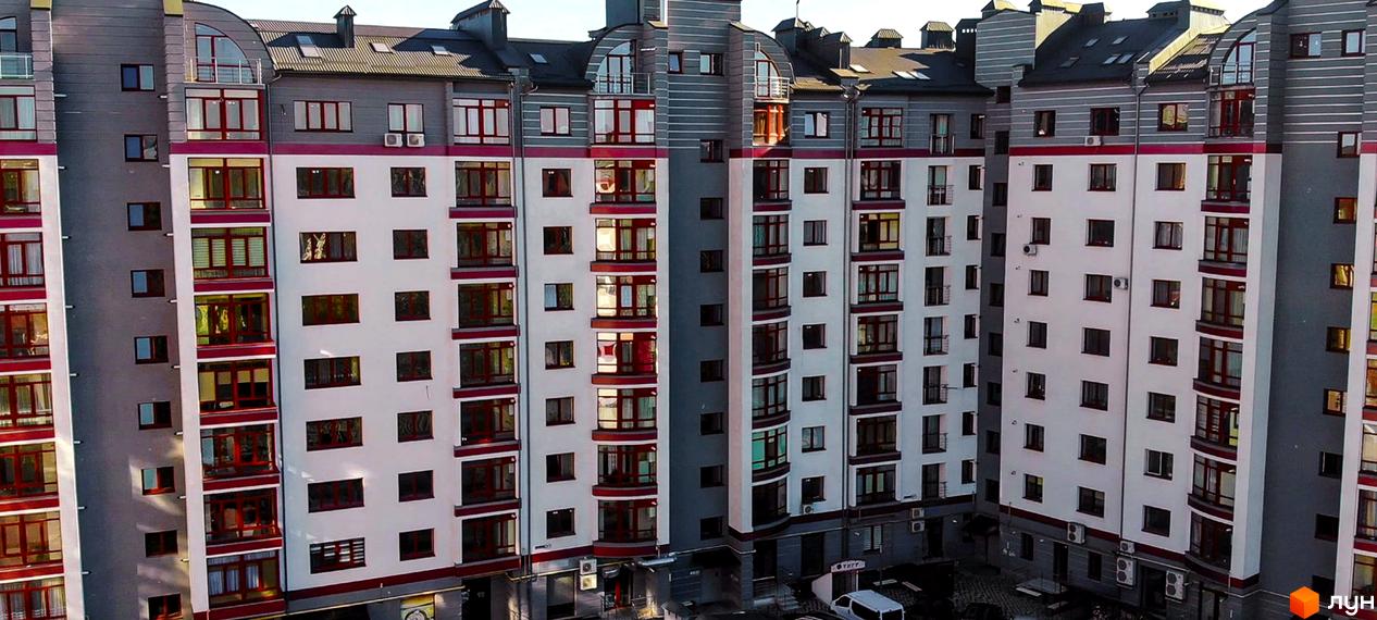 Фото фасаду житлового комплексу на вул. Вовчинецька / вул. Коломийської. Багатоповерховий будинок з великими вікнами та сіро-білим оздобленням.