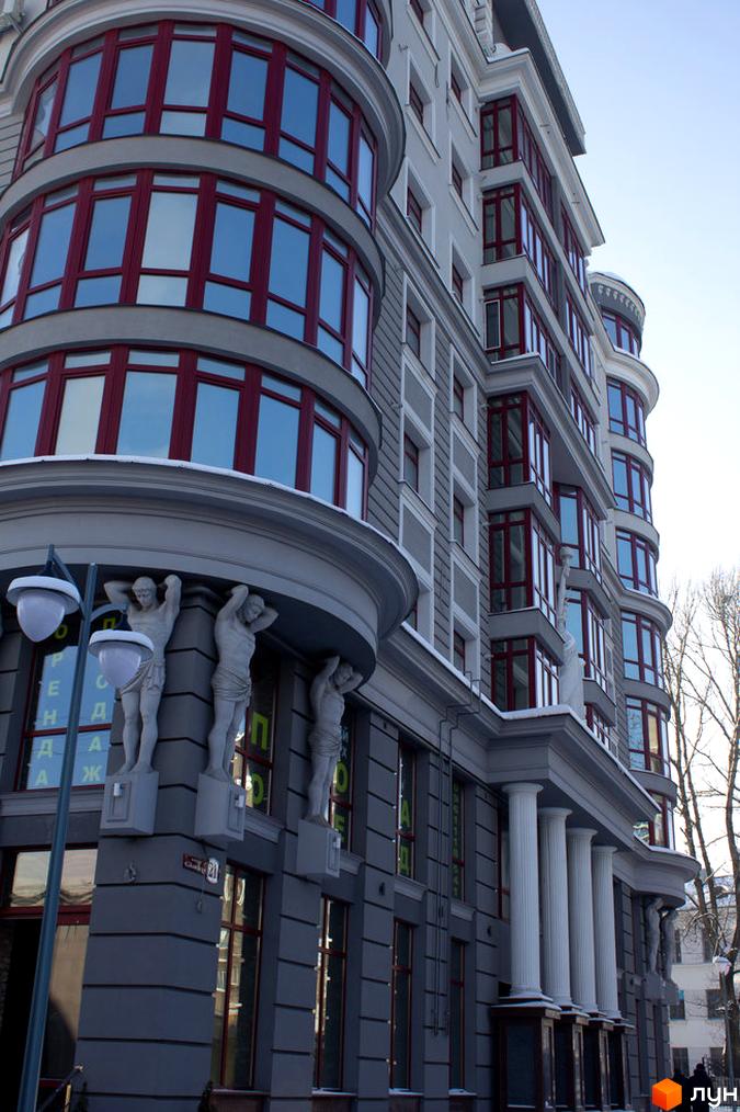 Житловий комплекс Статус: фасад будівлі з еркерними вікнами та колонами. Зовнішній вигляд новобудови з атлантами.