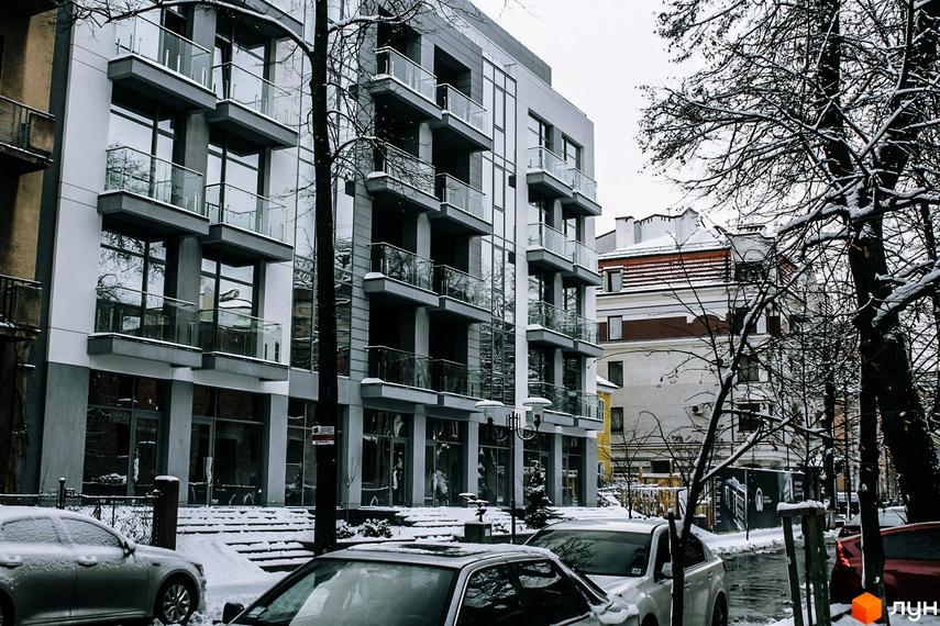 Новобудова ЖК Shevchenko з панорамними вікнами та балконами взимку. Навколо засніжена територія та дерева.