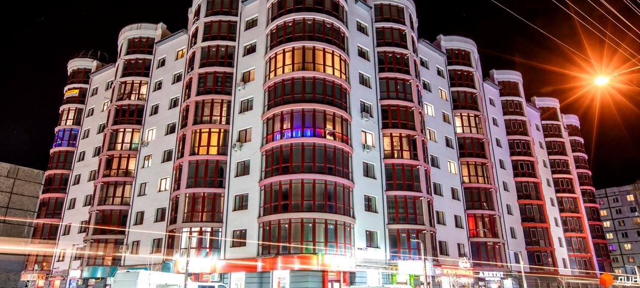 Зображення фасаду Житлового комплексу Red House II вночі. Багатоповерховий будинок з великими вікнами та освітленням.