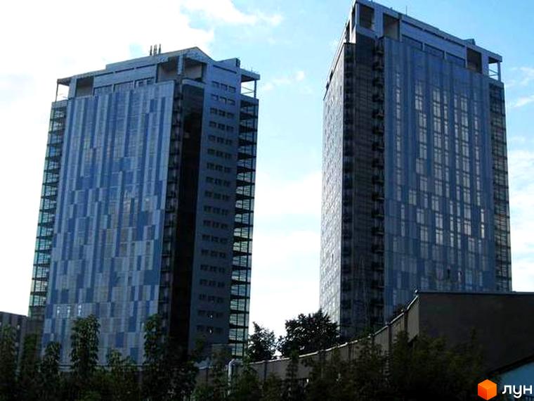 Житловий комплекс Ультра: дві висотні будівлі з темно-синіми скляними фасадами, одна з яких має візерунковий фасад, оточені зеленню.