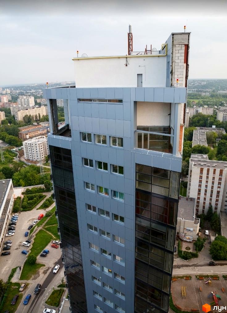 Житловий комплекс Ультра: багатоповерхова будівля з сірим облицюванням та скляними фасадами, поруч з парковками та зеленими зонами.