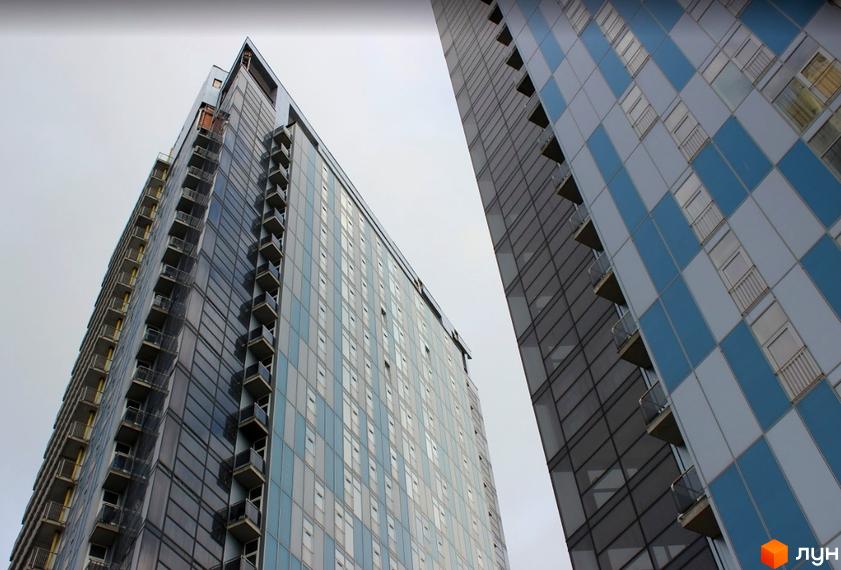 Житловий комплекс Ультра: висотні житлові будинки з численними вікнами та балконами. Фасад одного будинку має сіро-блакитний візерунок.