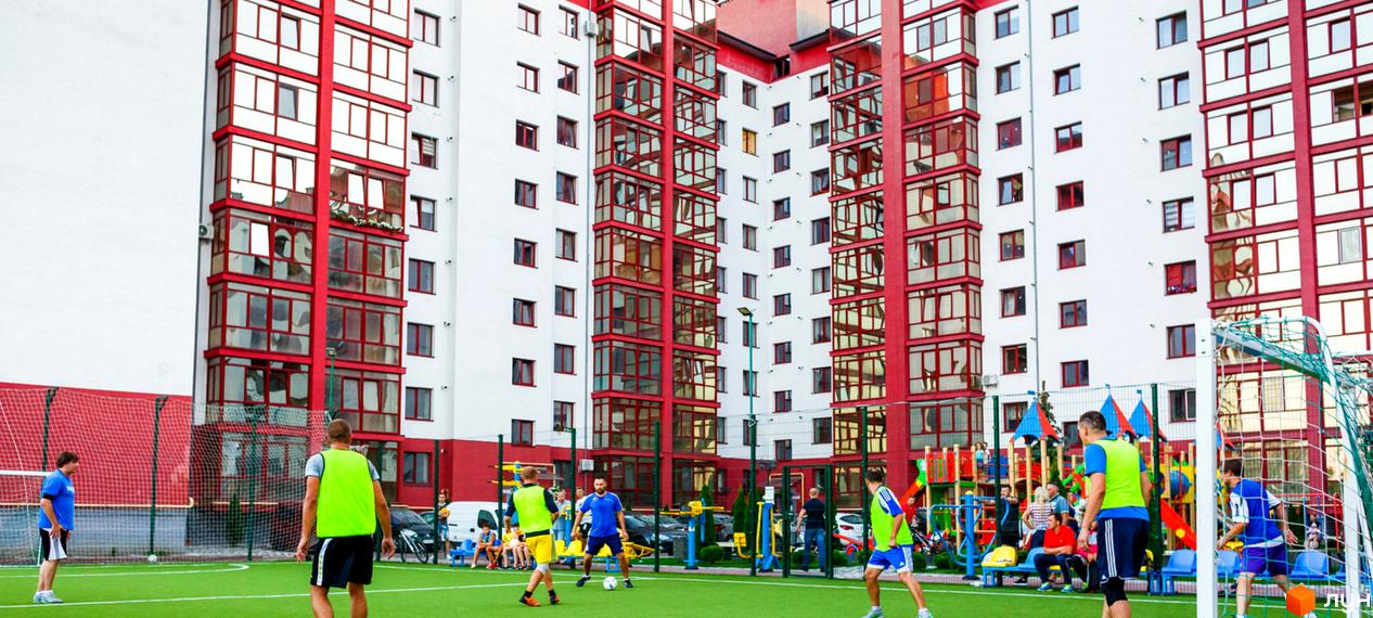 Зовнішній вигляд Житлового комплексу Європейський city з червоними балконами. На території комплексу розташований дитячий майданчик та футбольне поле.