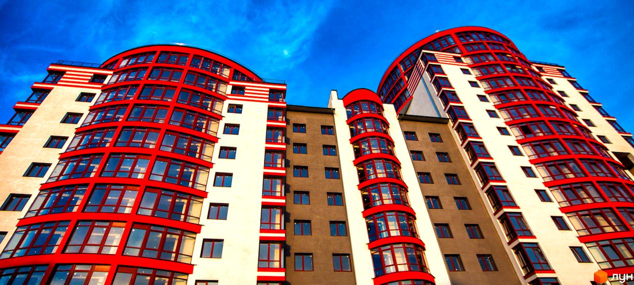 Зображення фасаду Житлового району Європейський city з червоними вставками. Багатоповерховий будинок на фоні блакитного неба.