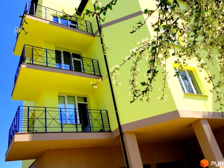 Житловий комплекс Тихорецький з жовтою фасадною стіною та балконами. Прибудинкова територія з зеленими насадженнями.