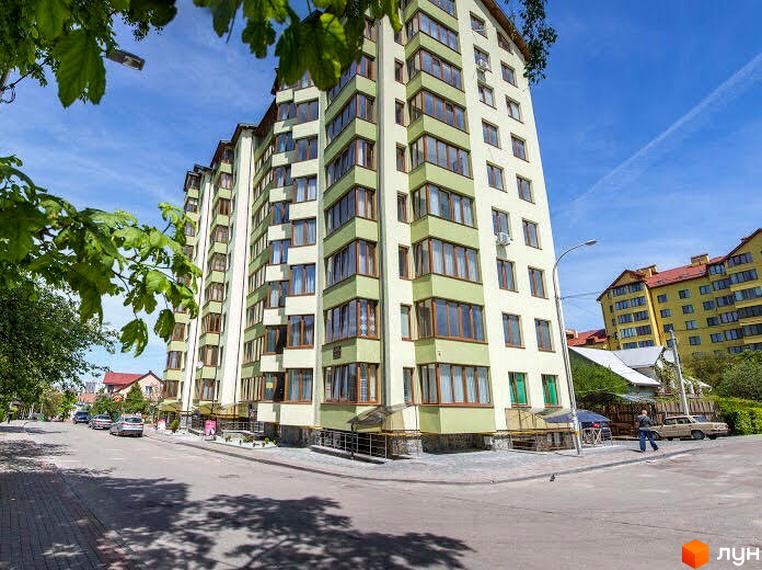 Багатоповерховий житловий будинок світлого кольору з зеленими секціями та великими вікнами на вул. Степана Бандери, 35. Поруч дорога та зелені насадження.