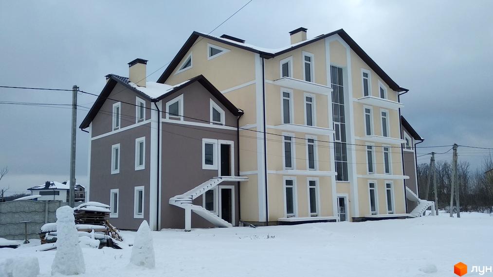 Зимовий краєвид з будинком. Житловий комплекс з двома поверхами та великою кількістю вікон. На території сніг, є сніговики.