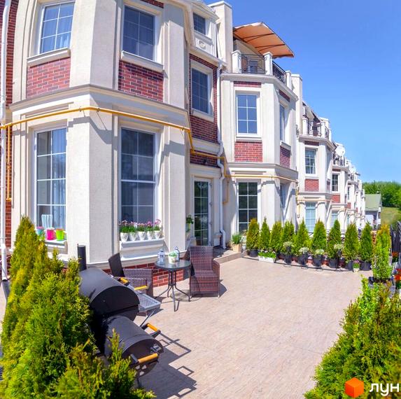 Таунхауси Royal Hill з цегляним фасадом та великими вікнами. Прибудинкова територія з терасою, грилем та зеленими насадженнями.