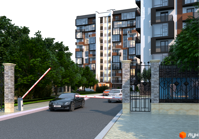 Зовнішній вигляд новобудови ЖК Перлина Проскурова з кількома автомобілями біля в'їзду та шлагбаумом. Територія комплексу огороджена парканом та має зелені насадження.