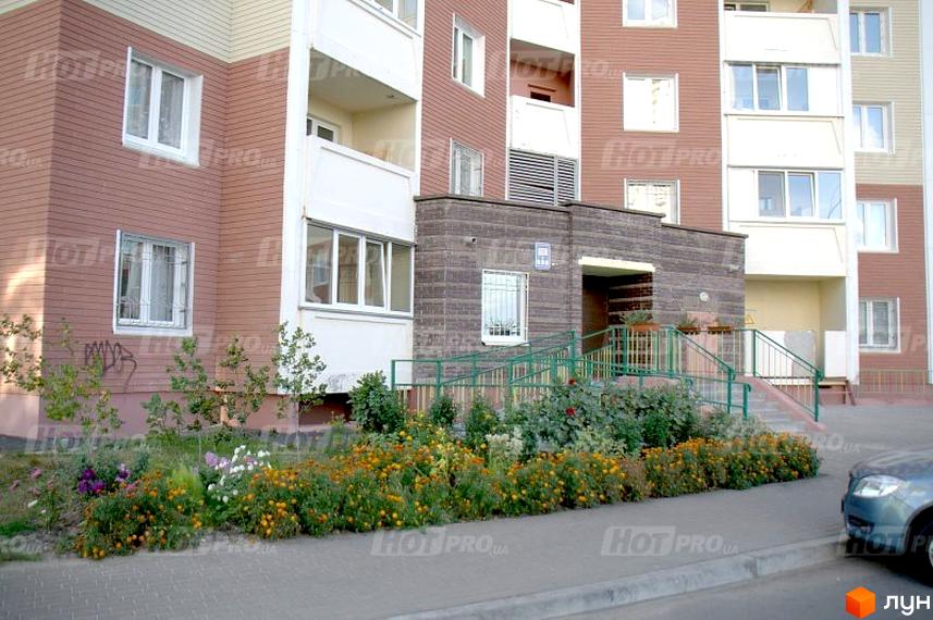 Зовнішній вигляд житлового комплексу на вул. Милославська, 8, 12. Озеленена прибудинкова територія з квітами та деревами.