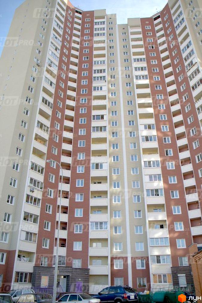 Багатоповерховий житловий комплекс на вулиці Милославська, 8, 12. Будинок має цегляно-бежевий фасад з червоними вставками та численними балконами. Біля будинку припарковані автомобілі.