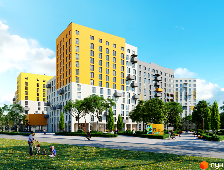 Житловий комплекс Riel City з жовтими та сірими фасадами, що складається з кількох секцій різної висоти. На передньому плані зелена галявина з людьми, що відпочивають.