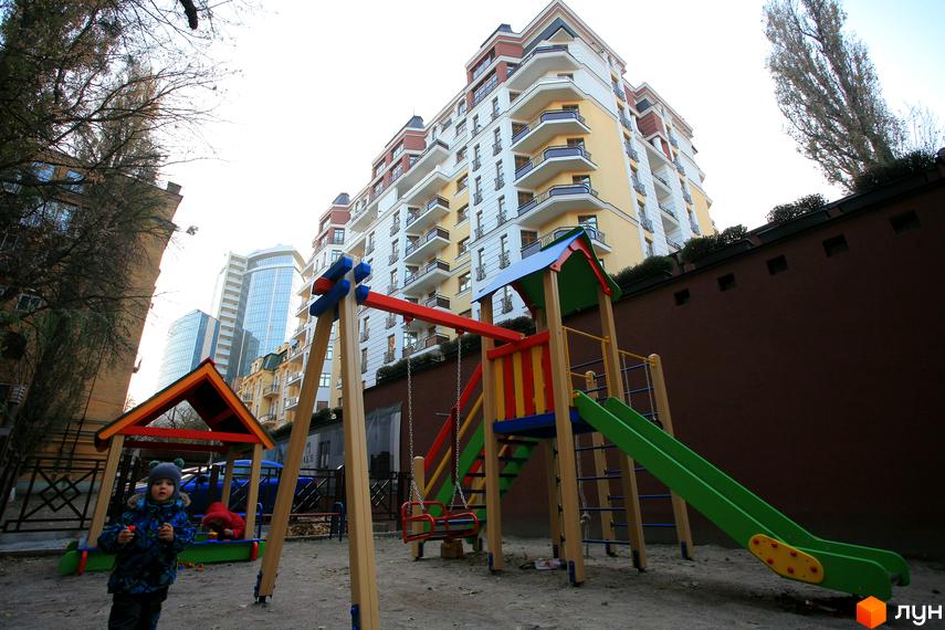 Новобудова ARCH House з яскравим дитячим майданчиком та гойдалкою. Комплекс має багатоповерхові будівлі з балконами та сучасний фасад.