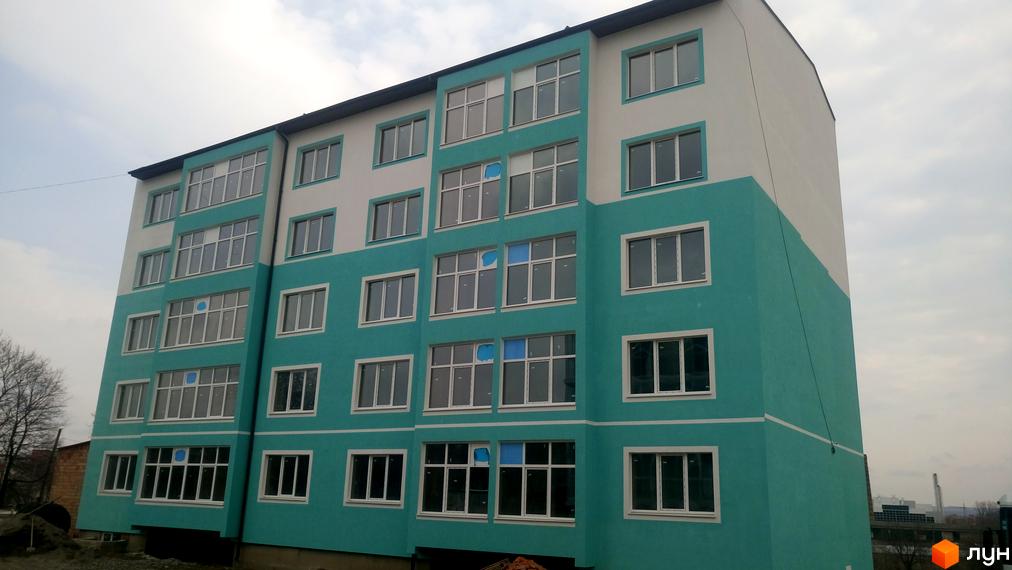 Зовнішній вигляд багатоповерхового будинку в Житловому комплексі Молодіжний XXI. Фасад будинку пофарбований у білий та бірюзовий кольори.