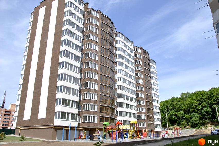 Зовнішній вигляд житлового комплексу Європейський квартал з цегляним фасадом та великою кількістю вікон. Поруч розташований дитячий майданчик.