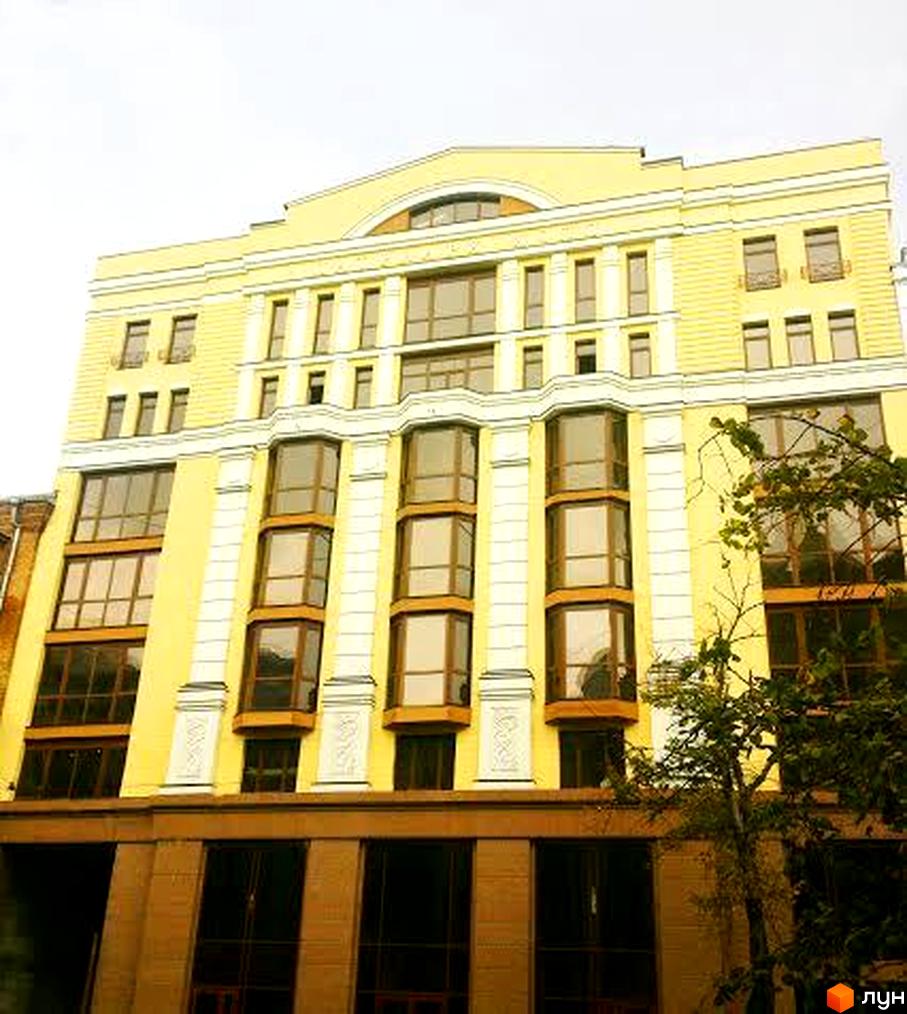 Житловий комплекс „Патріарх Холл“ з фасадом жовтого кольору та великими вікнами. Поруч з будинком росте дерево.