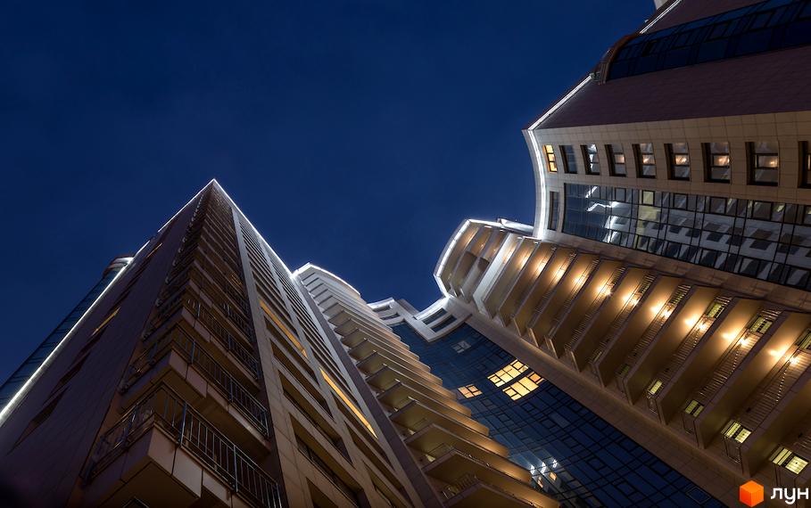 Житловий комплекс Busov Hill у Києві. Сучасна архітектура з підсвічуванням фасадів, панорамними вікнами та балконами. Високі будівлі на тлі нічного неба.