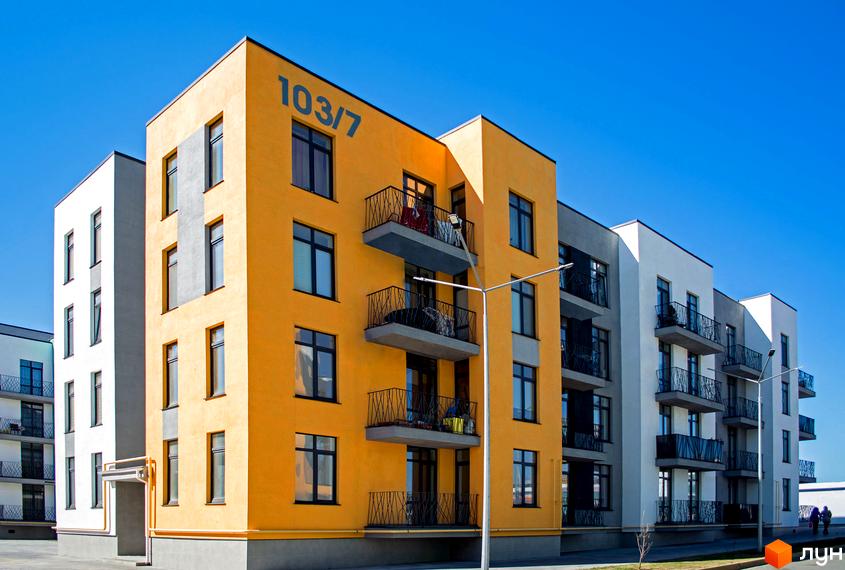 Житловий комплекс Європейка: яскрава жовта новобудова з балконами та вікнами на тлі блакитного неба. Поруч білі та сірі будинки.