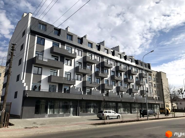 Новобудова ЖК Європа з сірими та білими фасадами, балконами та прибудинковою територією з автомобілями.