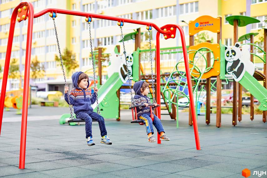 Діти граються на майданчику житлового комплексу Щасливий на Яблуневій. На території комплексу сучасні дитячі майданчики та зелені зони для відпочинку.