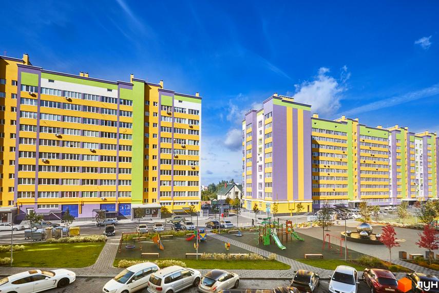 Житловий комплекс Щасливий на Яблуневій: яскраві фасади будівель та облаштований дитячий майданчик. Фото новобудови з паркуванням та зеленими зонами.