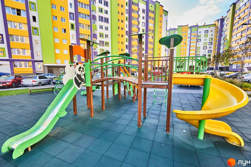 Яскраві новобудови ЖК Щасливий на Яблуневій з дитячим майданчиком. Зелена гірка та жовта спіральна гірка для дітей.