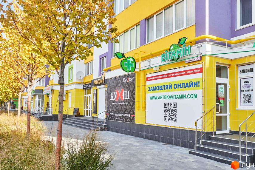 Житловий комплекс Щасливий на Яблуневій, 136. Фасад новобудови з жовтими та фіолетовими елементами, поруч дерева з осіннім листям.