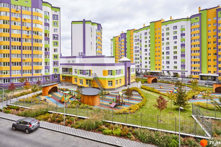 Житловий комплекс Щасливий на Яблуневій: яскраві багатоповерхівки та дитячий майданчик з різнокольоровим покриттям. Сучасний житловий комплекс з упорядкованою прибудинковою територією.