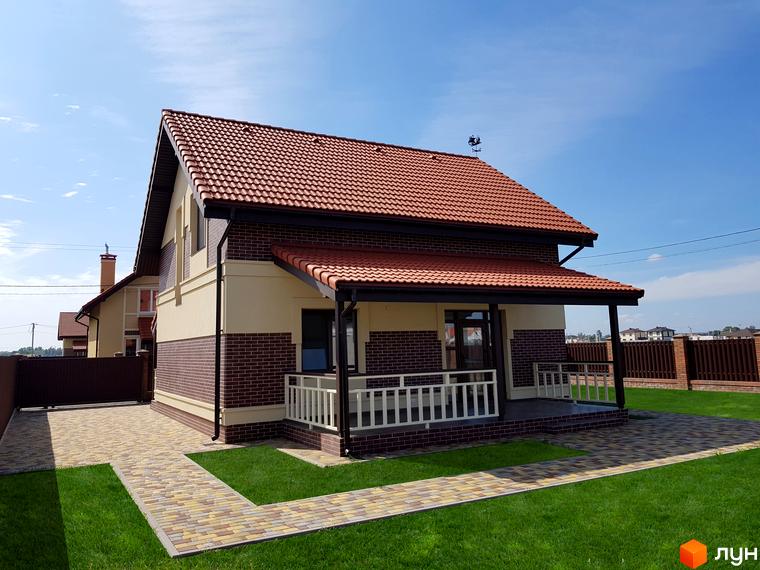 Котеджне містечко Сонячний. Зовнішній вигляд двоповерхового будинку з червоною черепицею та цегляними елементами, доглянута прибудинкова територія з газоном та вимощеними доріжками.