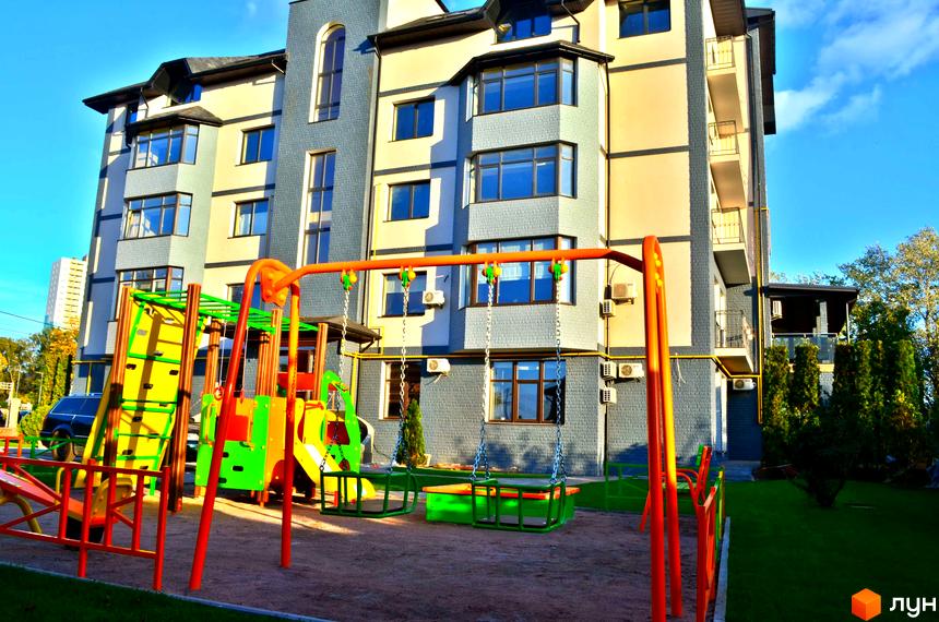 Житловий комплекс Ваша квартира з дитячим майданчиком. Фасад будинку виконано з цегли, на території є зелені насадження.