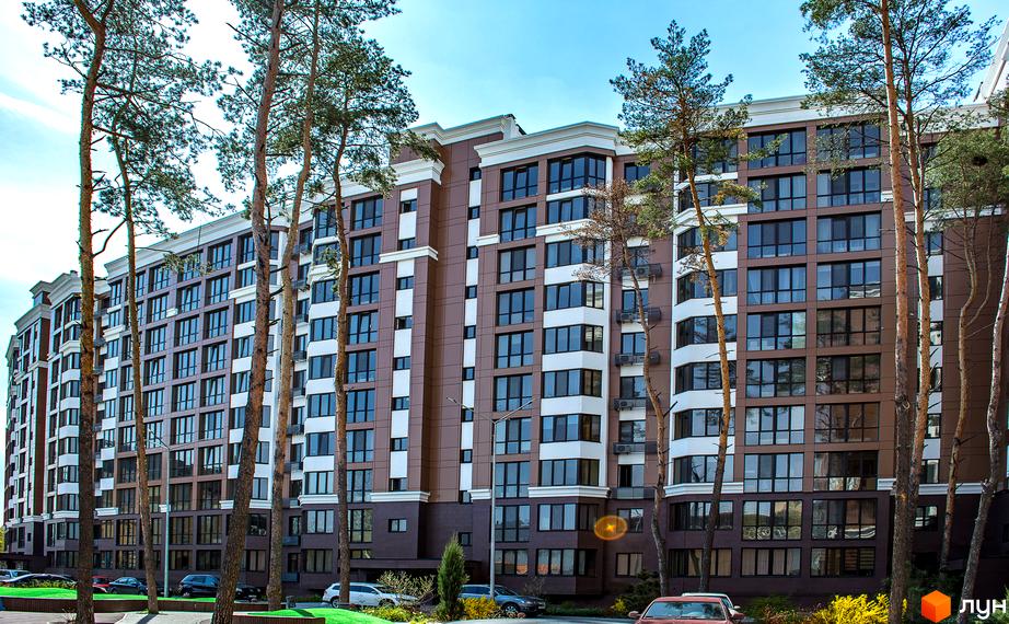 Зовнішній вигляд новобудови ЖК Echo Park з великою кількістю вікон та балконів. На прибудинковій території ростуть високі дерева, є зелені газони та припарковані автомобілі.