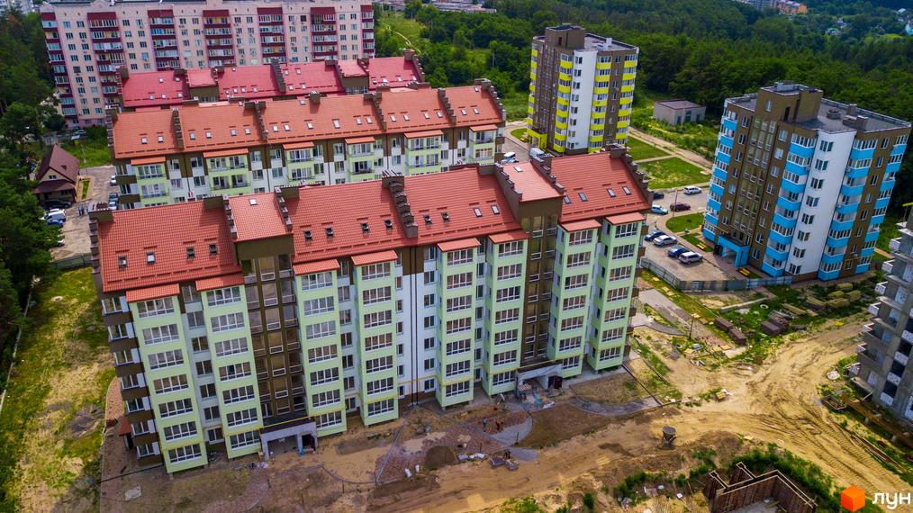 Житловий комплекс Обухівський ключ з червоними дахами та фасадами в зелених тонах. На прибудинковій території ведеться будівництво.