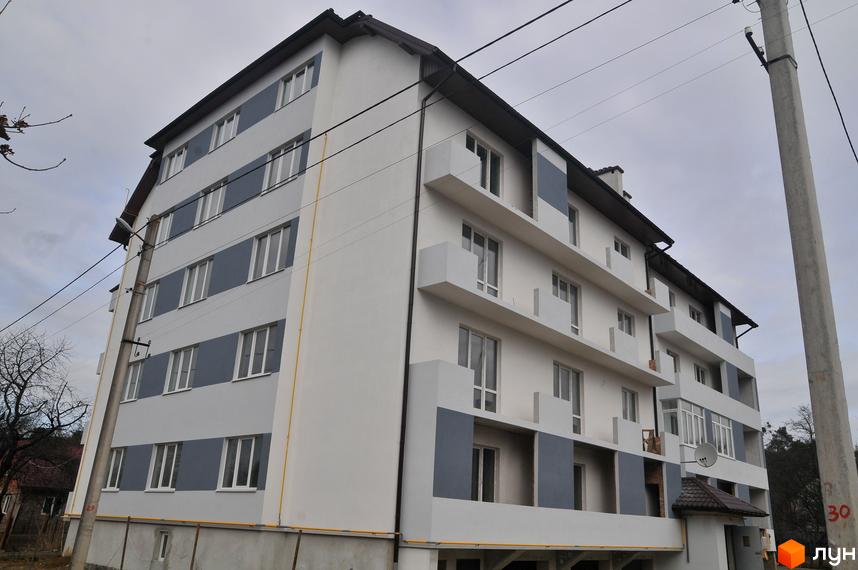 Багатоповерховий житловий будинок на вул. Ясна, 25, світло-сірого кольору з темними вставками та балконами. Видно дерева та електроопори.