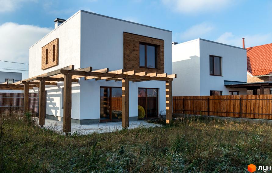 Котеджне містечко На Щасливій: білі двоповерхові будинки з дерев'яними акцентами та перголою. Огороджена територія з дерев'яним парканом.