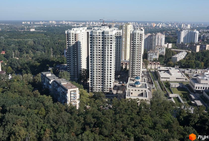 Зовнішній вигляд висотних будівель житлового комплексу Зелений острів-2 на фоні міського пейзажу та зелених насаджень. Фотографія демонструє архітектуру новобудови та прибудинкову територію.
