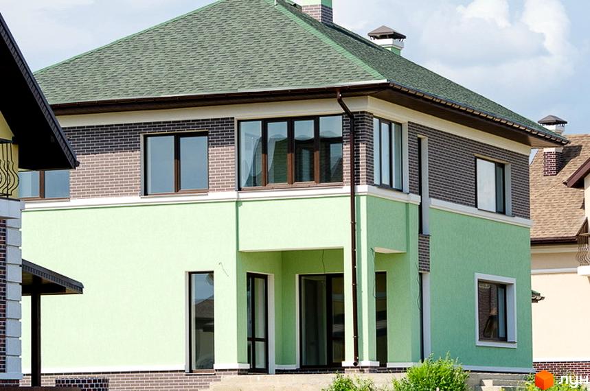 Зовнішній вигляд двоповерхового будинку з зеленою черепичною покрівлею та світло-зеленими стінами. Навколо будинку видно зелені насадження та сусідні будинки.