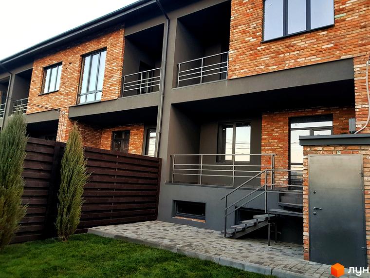 Таунхауси „Пушкінський“: фасади з цегли та сірої штукатурки, балкони з металевими перилами, сходи та двері. Прибудинкова територія з газоном та дерев'яним парканом.