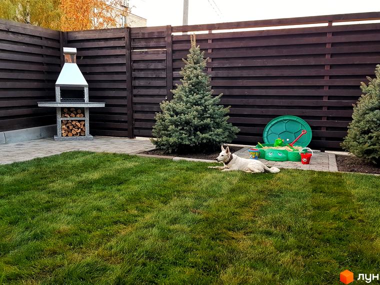 Таунхауси Пушкінський: барбекю зона та дитячий пісочник біля будинку. Зелений газон та хвойні дерева на подвір'ї.