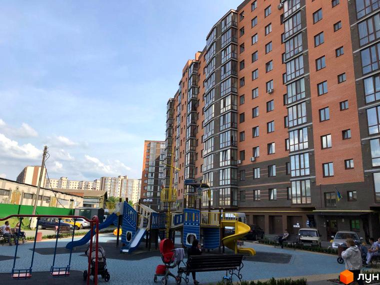 Зображення фасаду та дитячого майданчика Житлового комплексу Сімейний. Вигляд новобудови та прибудинкової території.