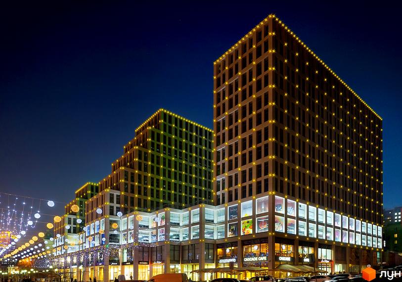 Житловий комплекс Cascade Plaza з сучасною архітектурою та прибудинковою територією, освітленою вечірніми вогнями.
